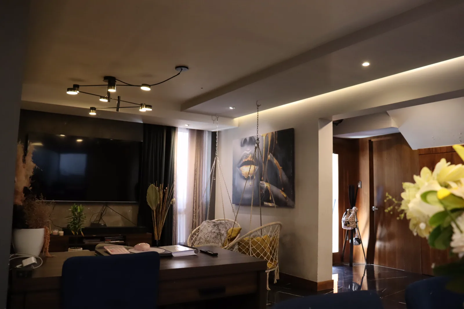 Sala con la pantalla empotrada, las sillas colgantes y el cuadro de gran formato.