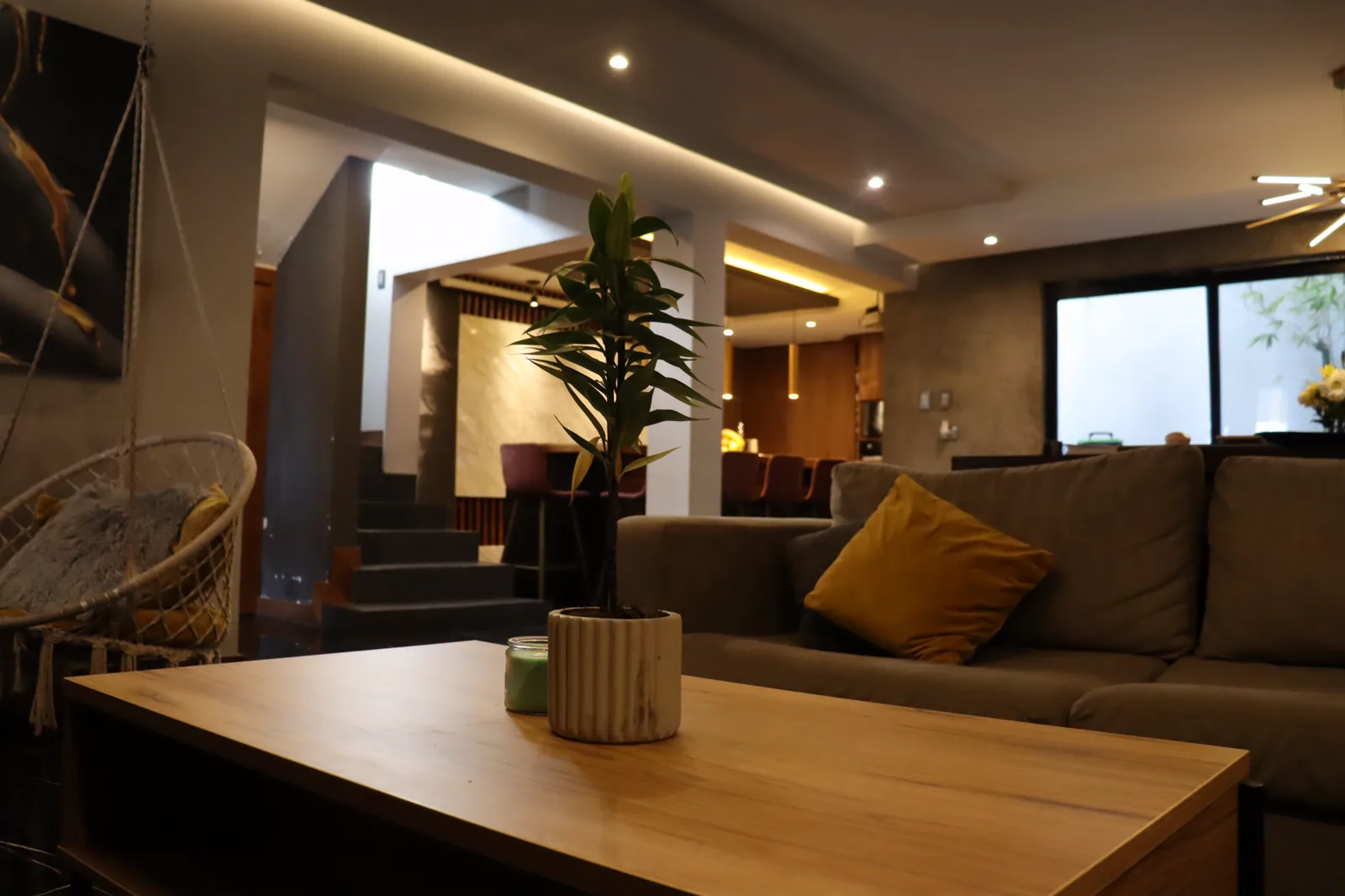 Sala con sillón gris, cojines mostaza y mesa de centro de madera.