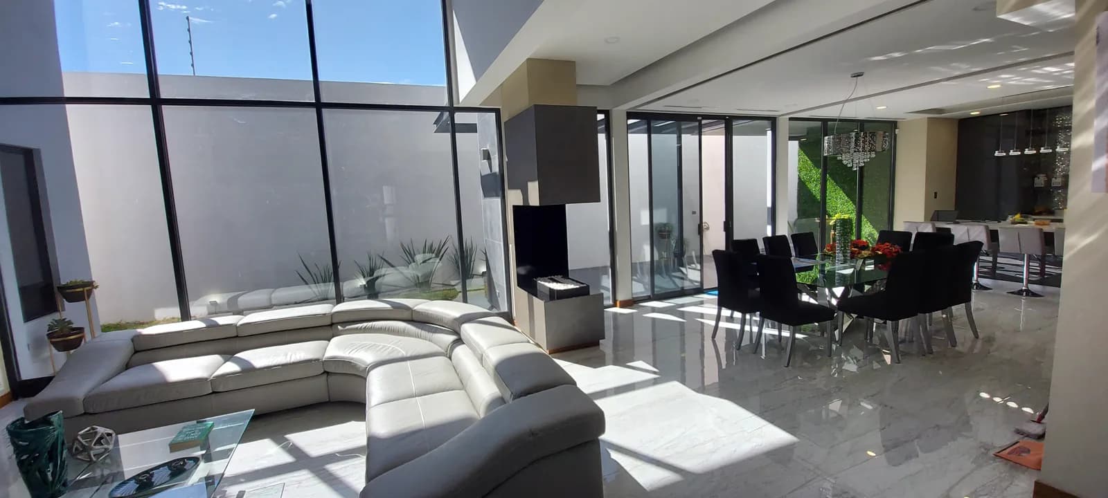 Sala y comedor con ventanales de piso a techo hacia el patio.