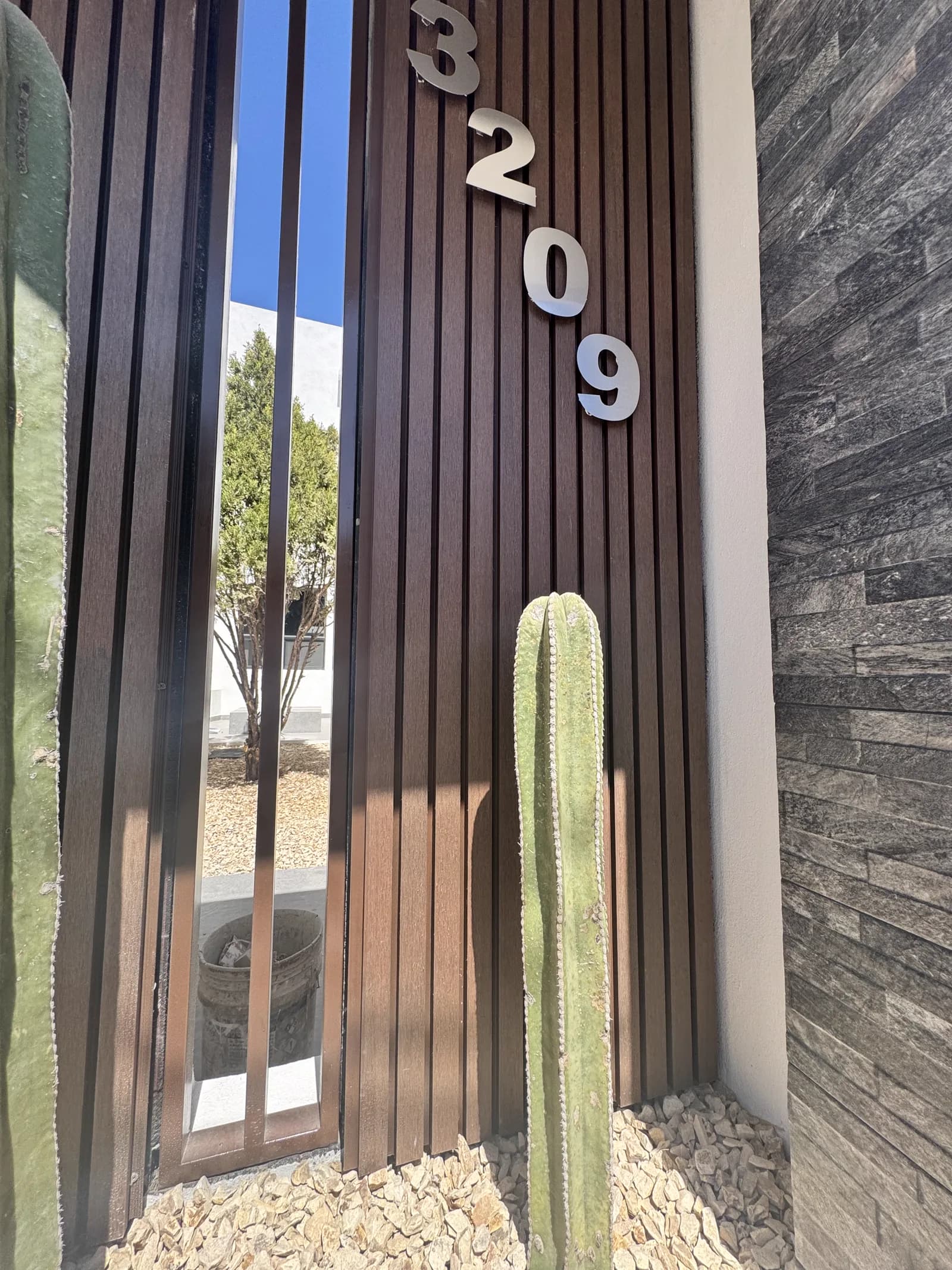 Números metálicos sobre el panel de listones de madera, junto a un cactus.