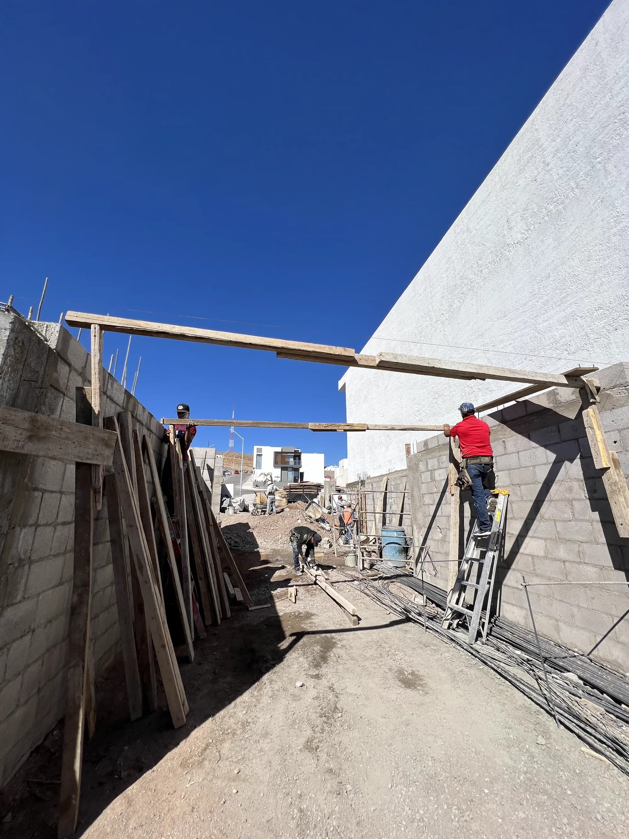 Cimbra de madera apuntalada contra el muro, con los trabajadores colocándola.