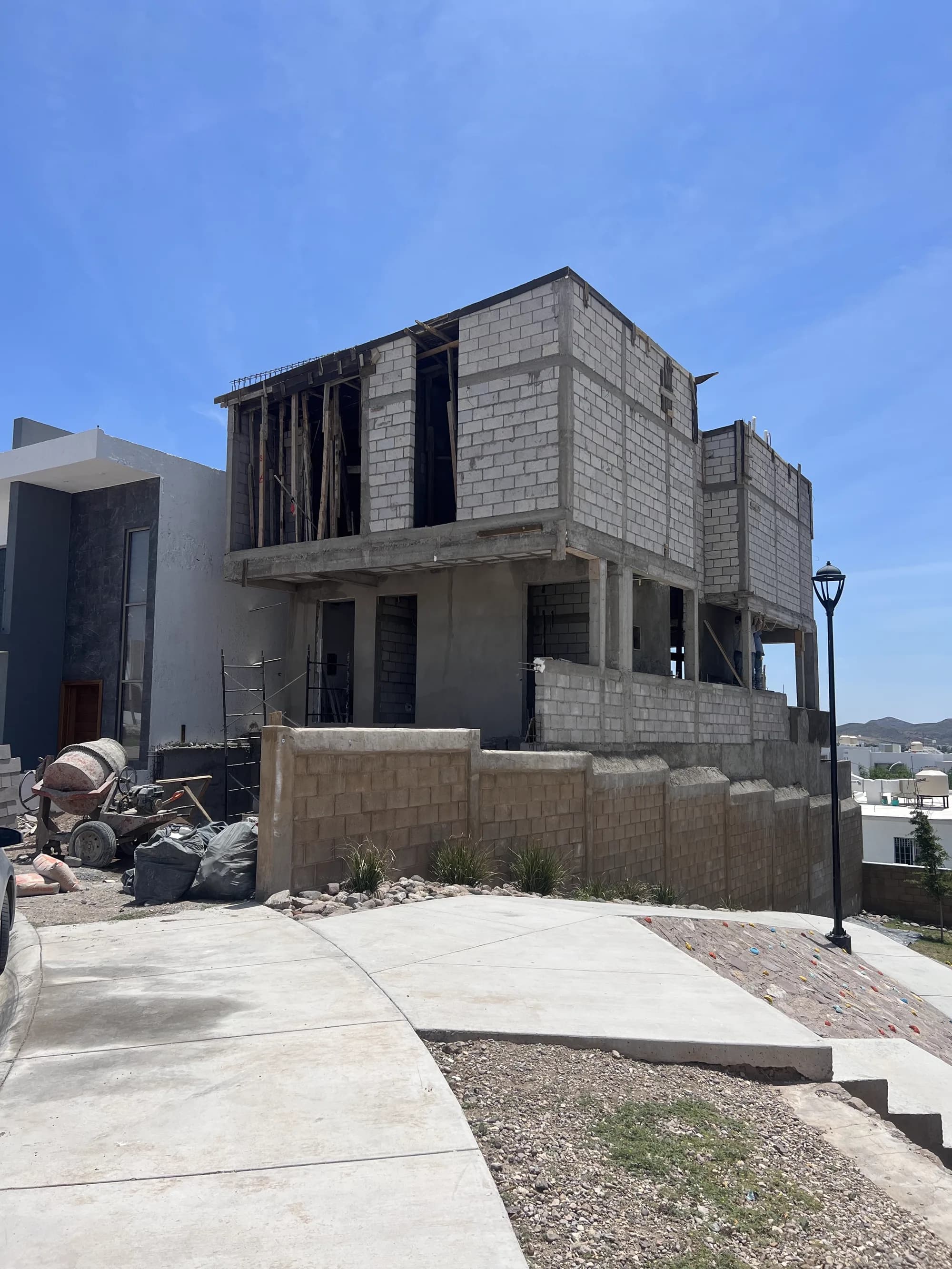 La casa en obra gris de dos niveles, vista desde la calle.