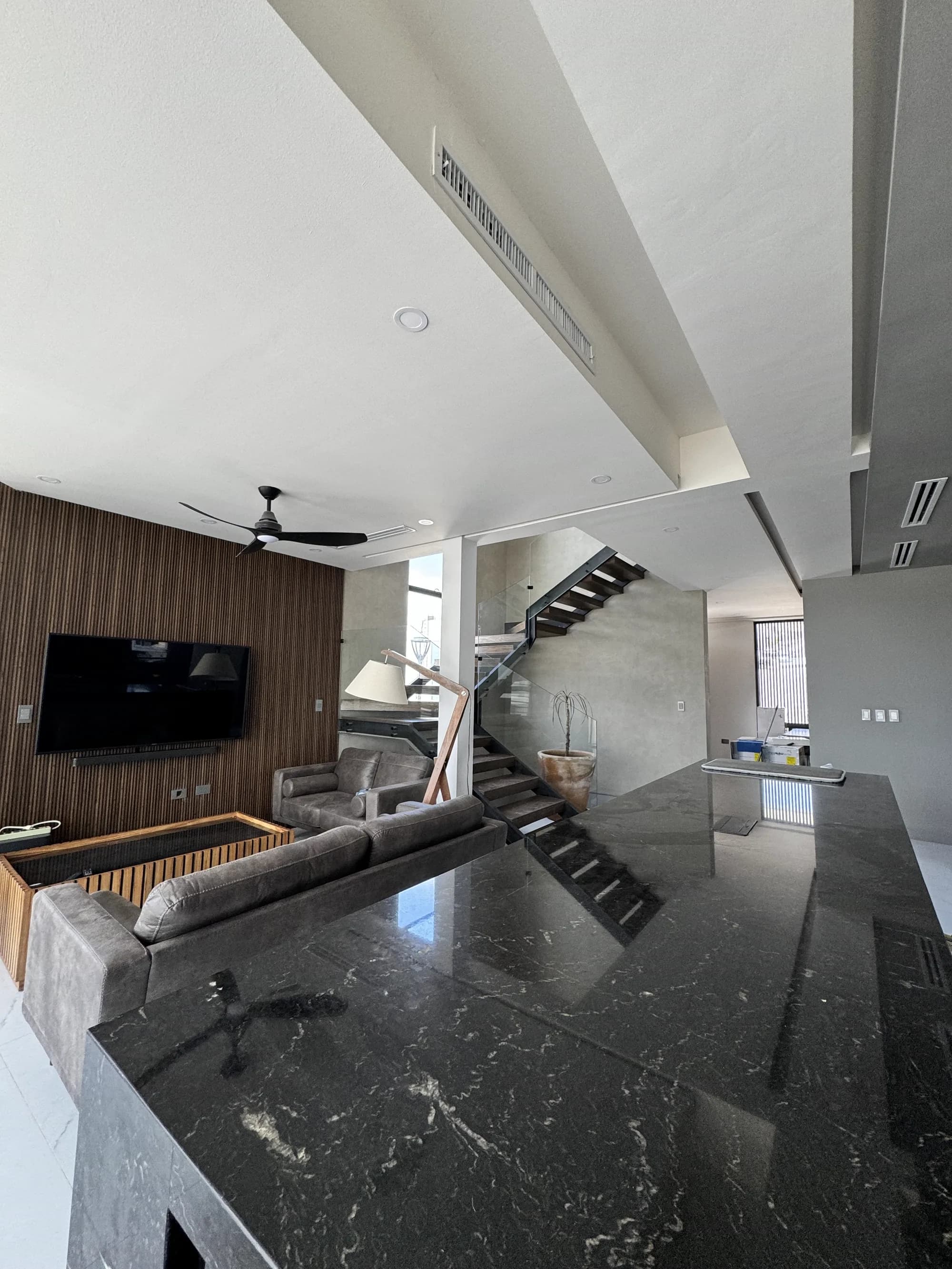 Sala terminada con el muro de listones de madera, la pantalla y la barra de mármol.