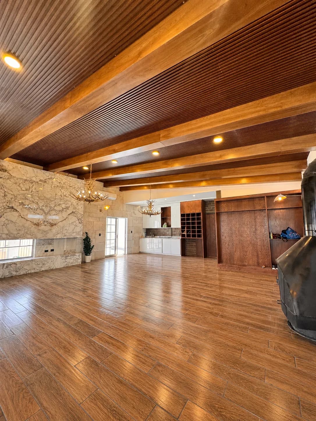 Salón con muro de piedra, libreros de madera y la chimenea negra en primer plano.