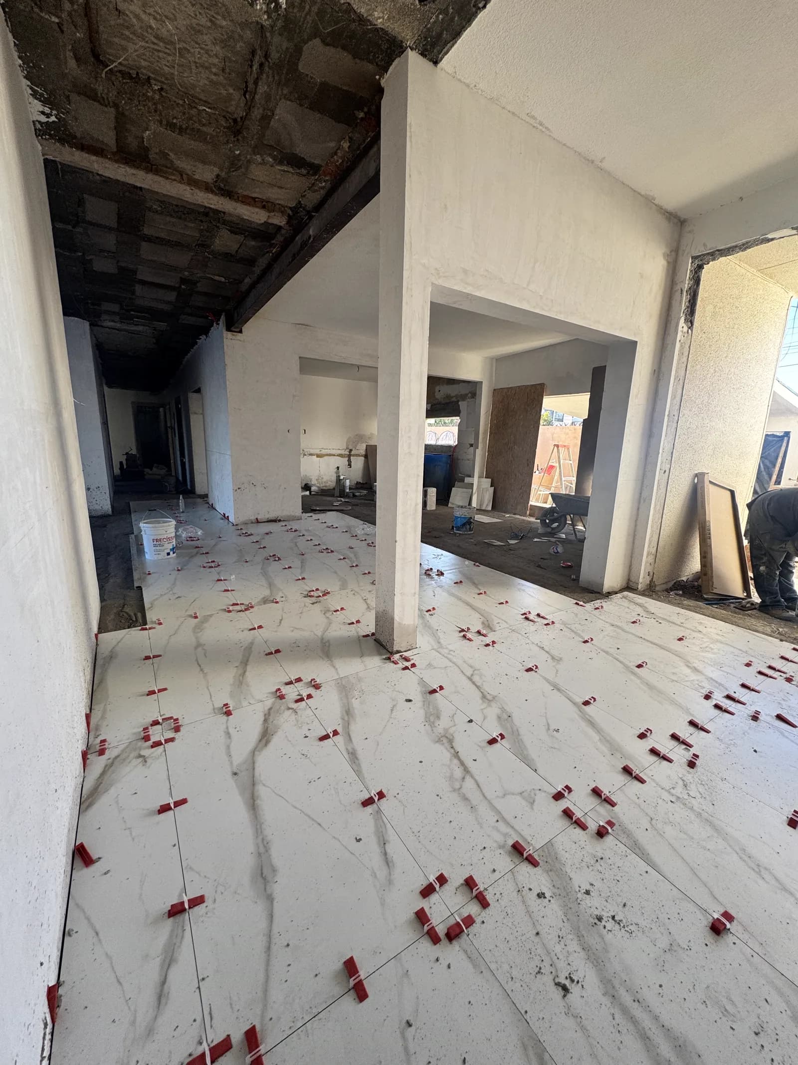 Colocación del porcelanato veteado, con las crucetas todavía en el piso.
