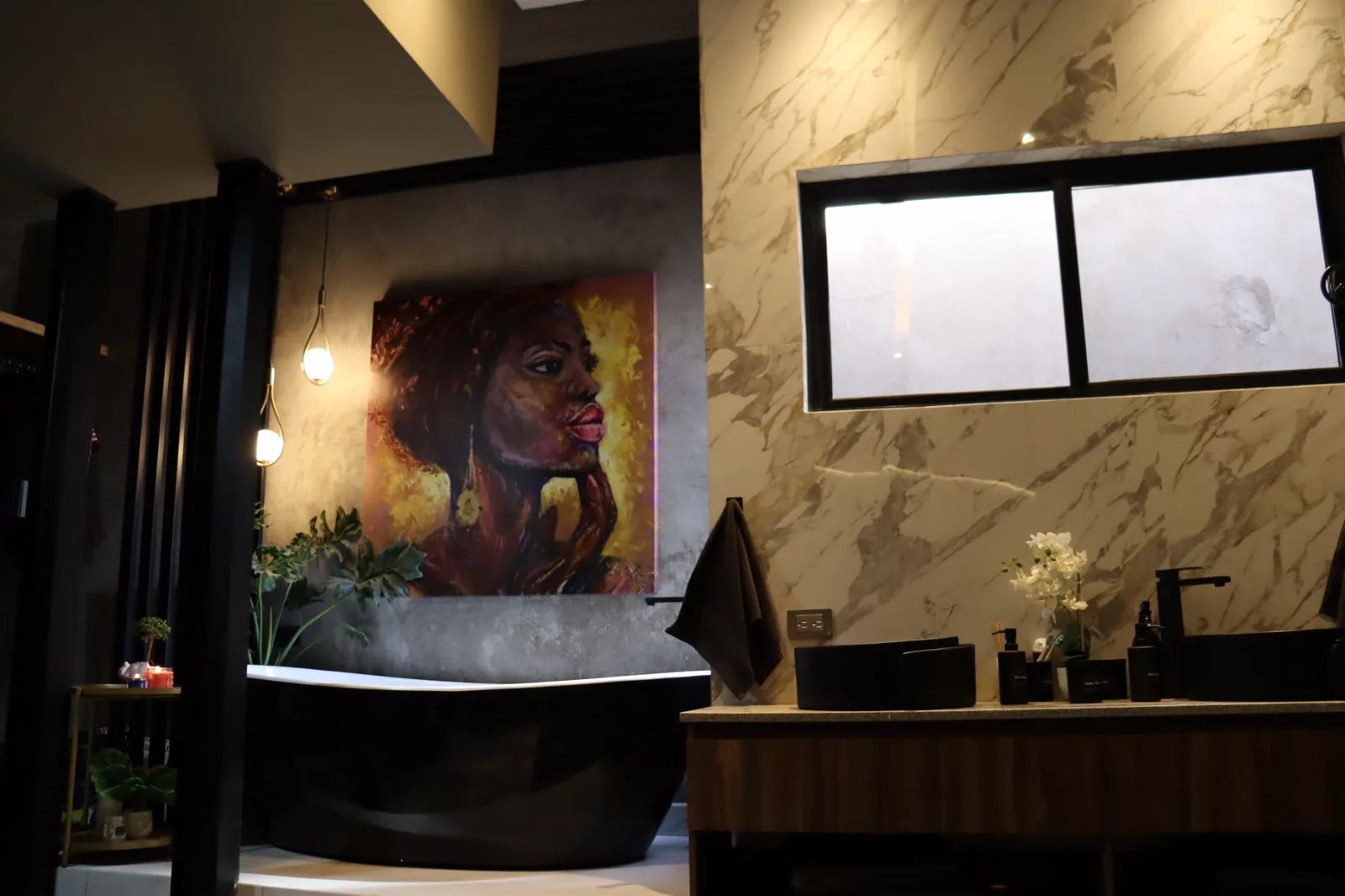 Baño con tina exenta, lavabo sobre mueble de madera y muro de porcelanato tipo mármol.