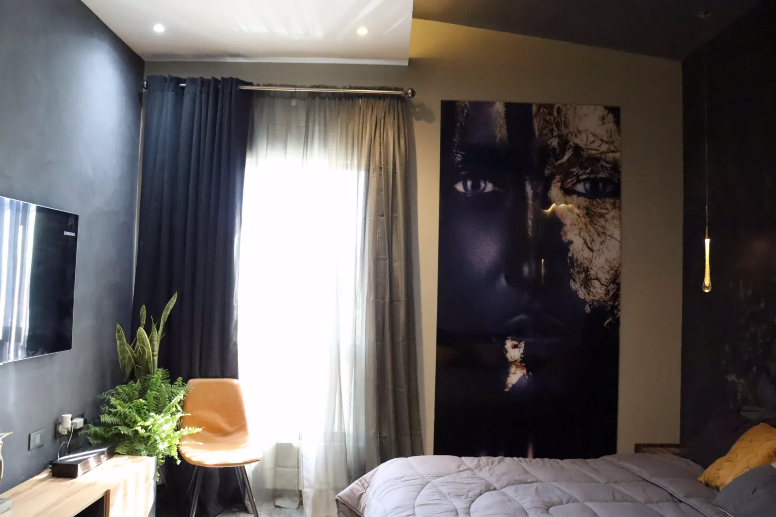 Rincón junto al ventanal, con cortinas oscuras, silla de piel y un cuadro vertical.