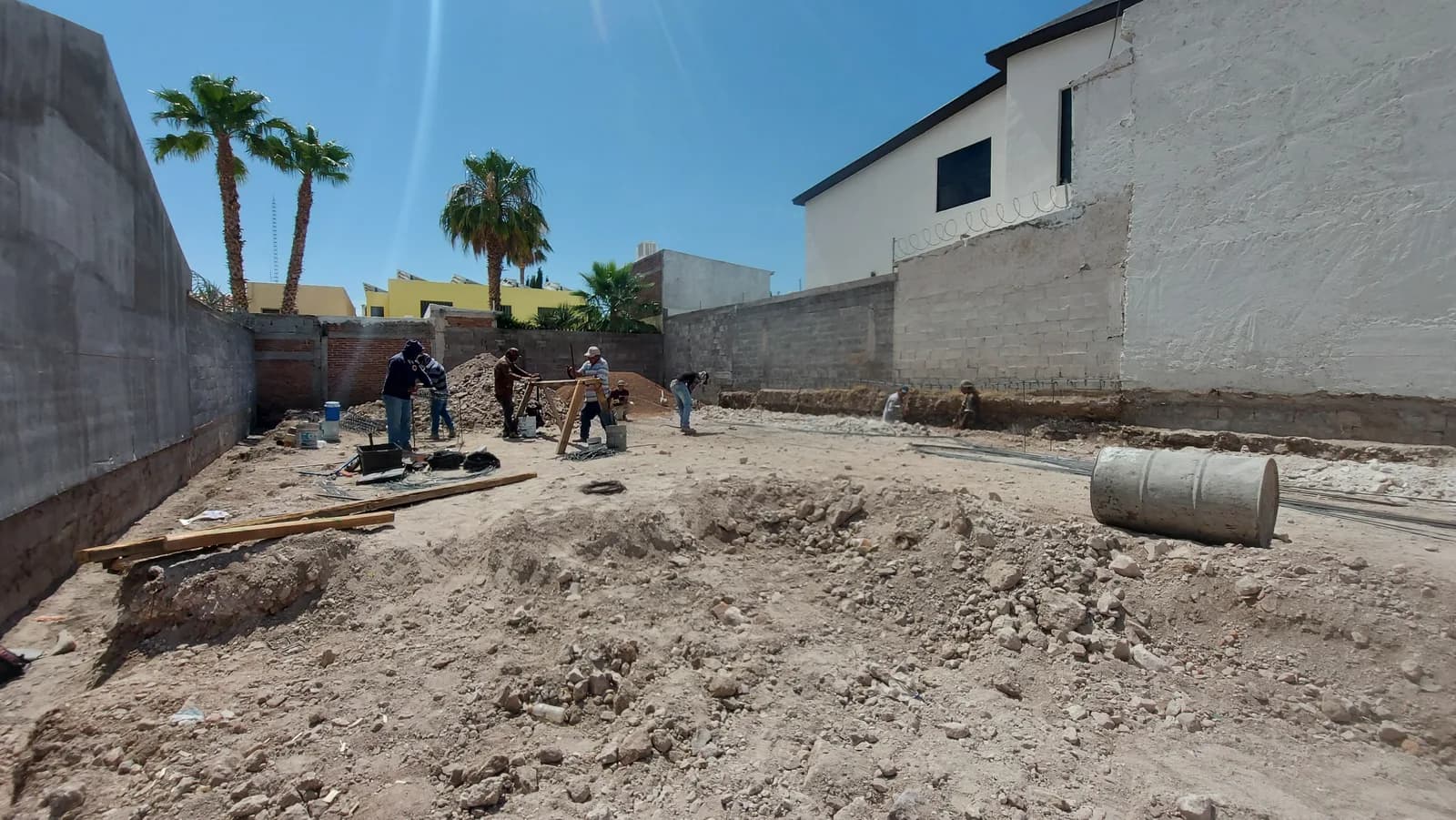 El terreno despalmado entre las bardas vecinas, con los trabajadores trazando la cimentación.