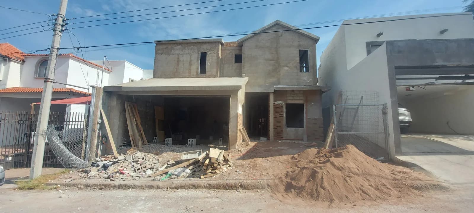 La casa en obra gris de dos niveles, vista desde la calle.