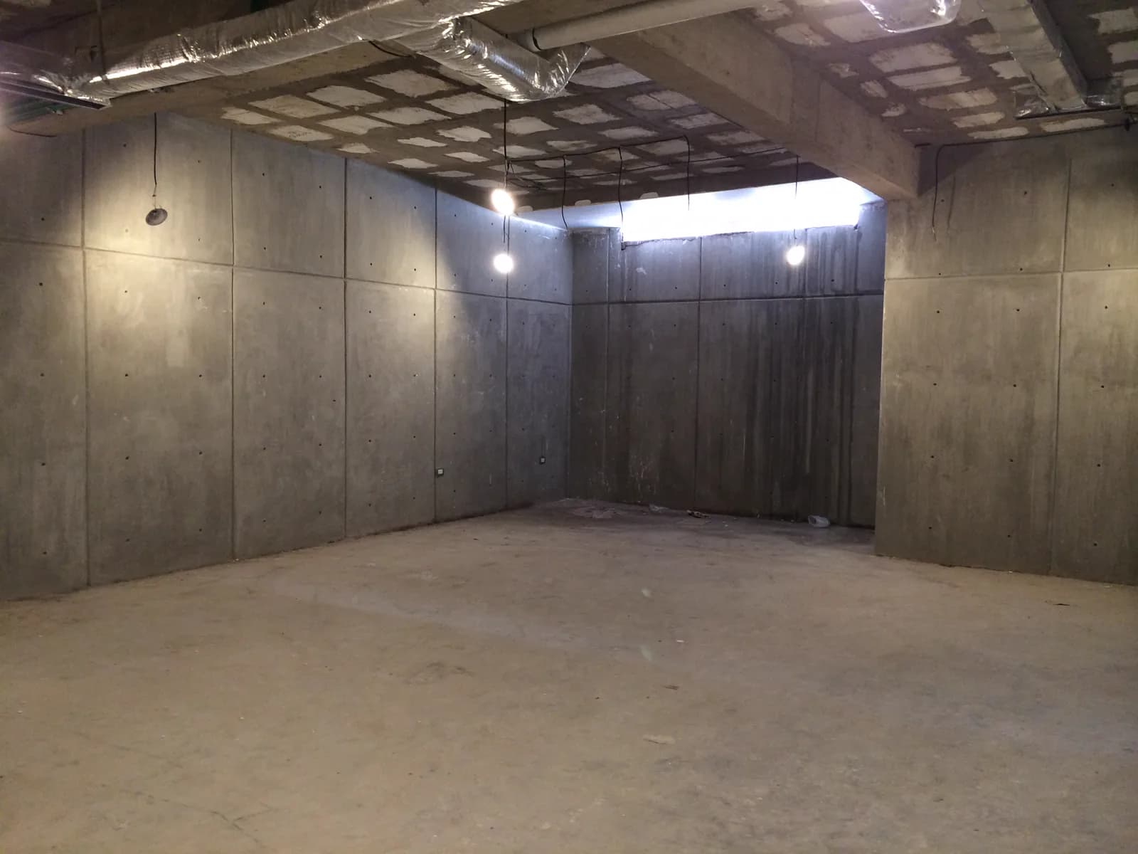 Cuarto del sótano con muros de concreto aparente y luz cenital.