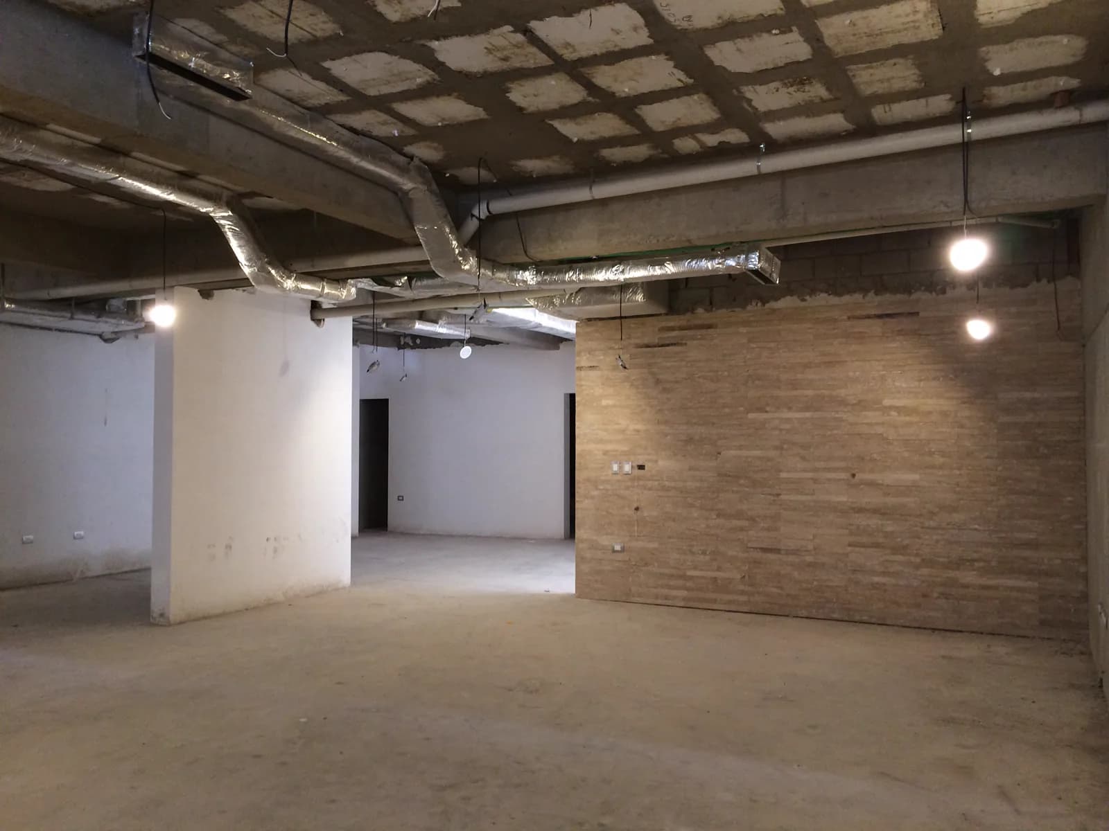 Sótano con un muro de ladrillo y muros ya aplanados en blanco.