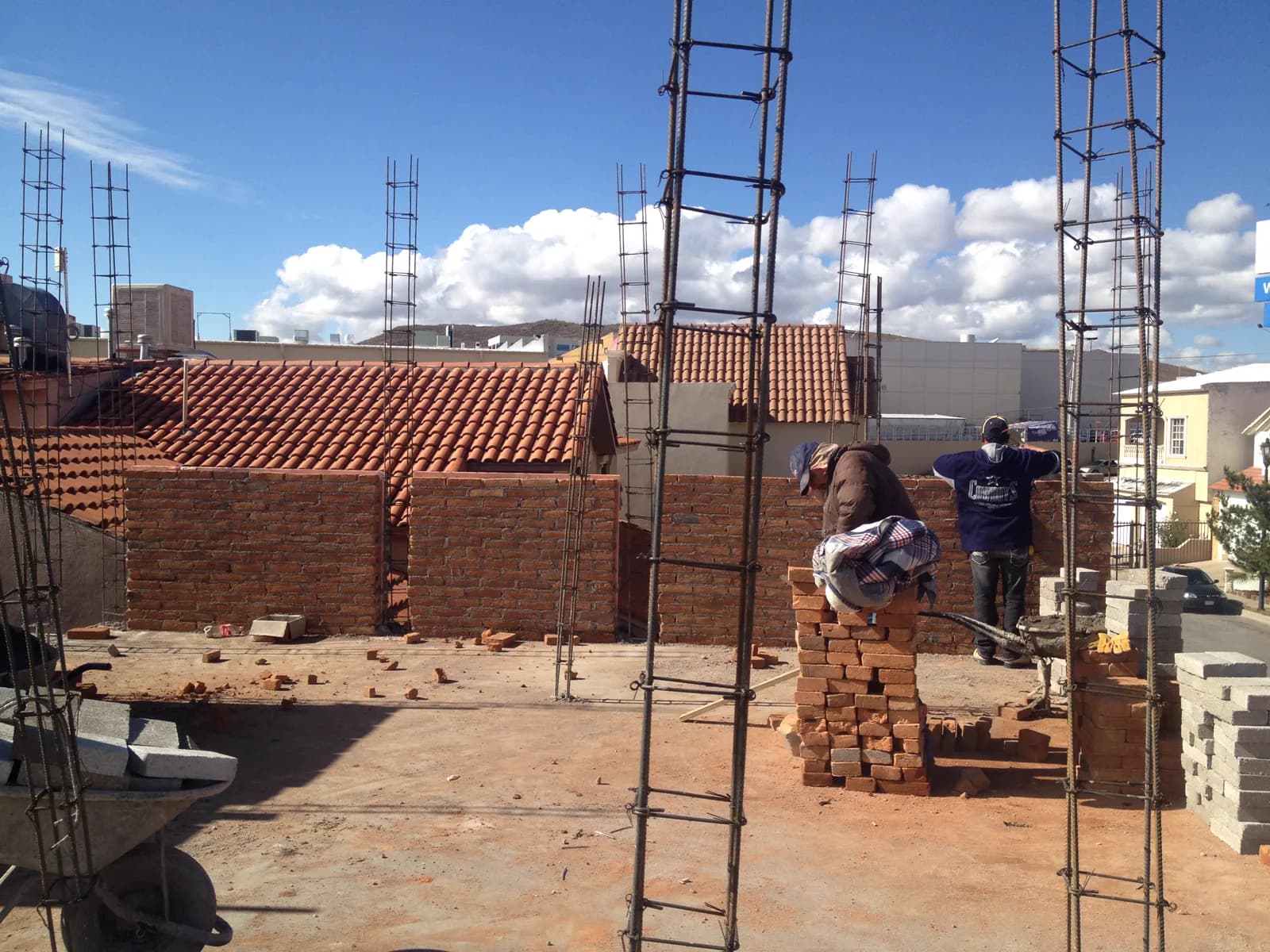 Trabajadores levantando muros de ladrillo en la planta alta.