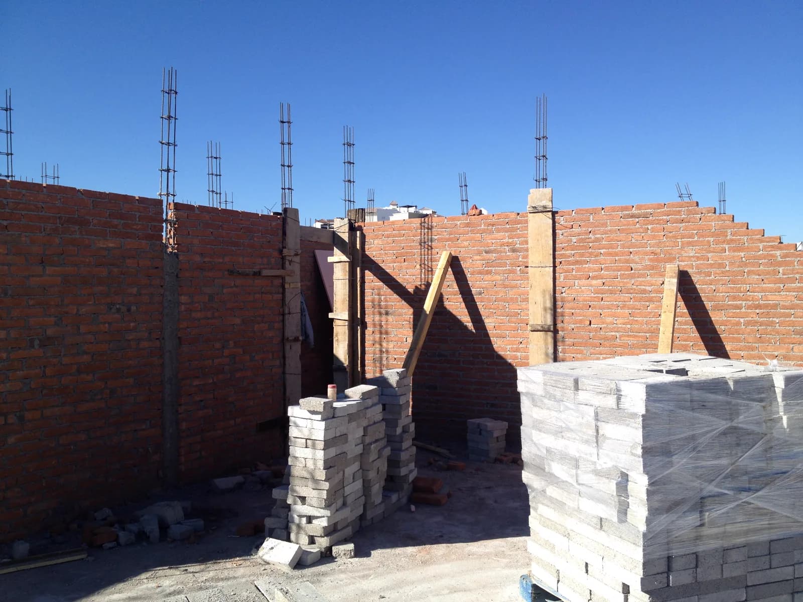 Muros de ladrillo en proceso y block apilado.