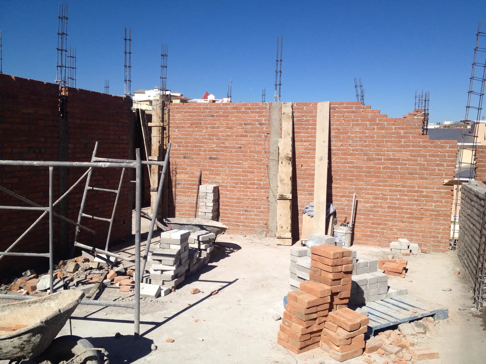 Muros de ladrillo con andamio y material en la losa.