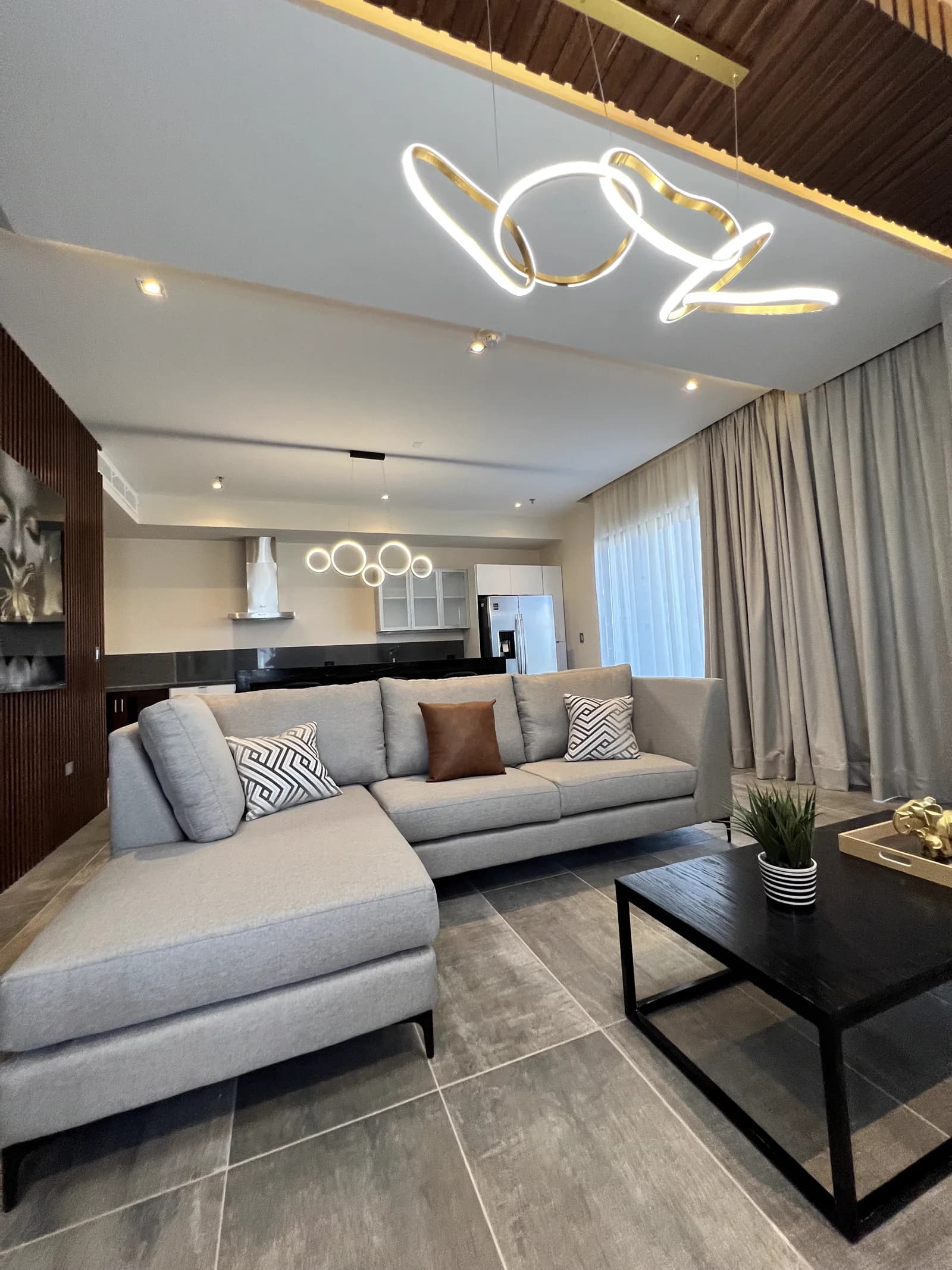 Sala con sillón en escuadra y la cocina al fondo.