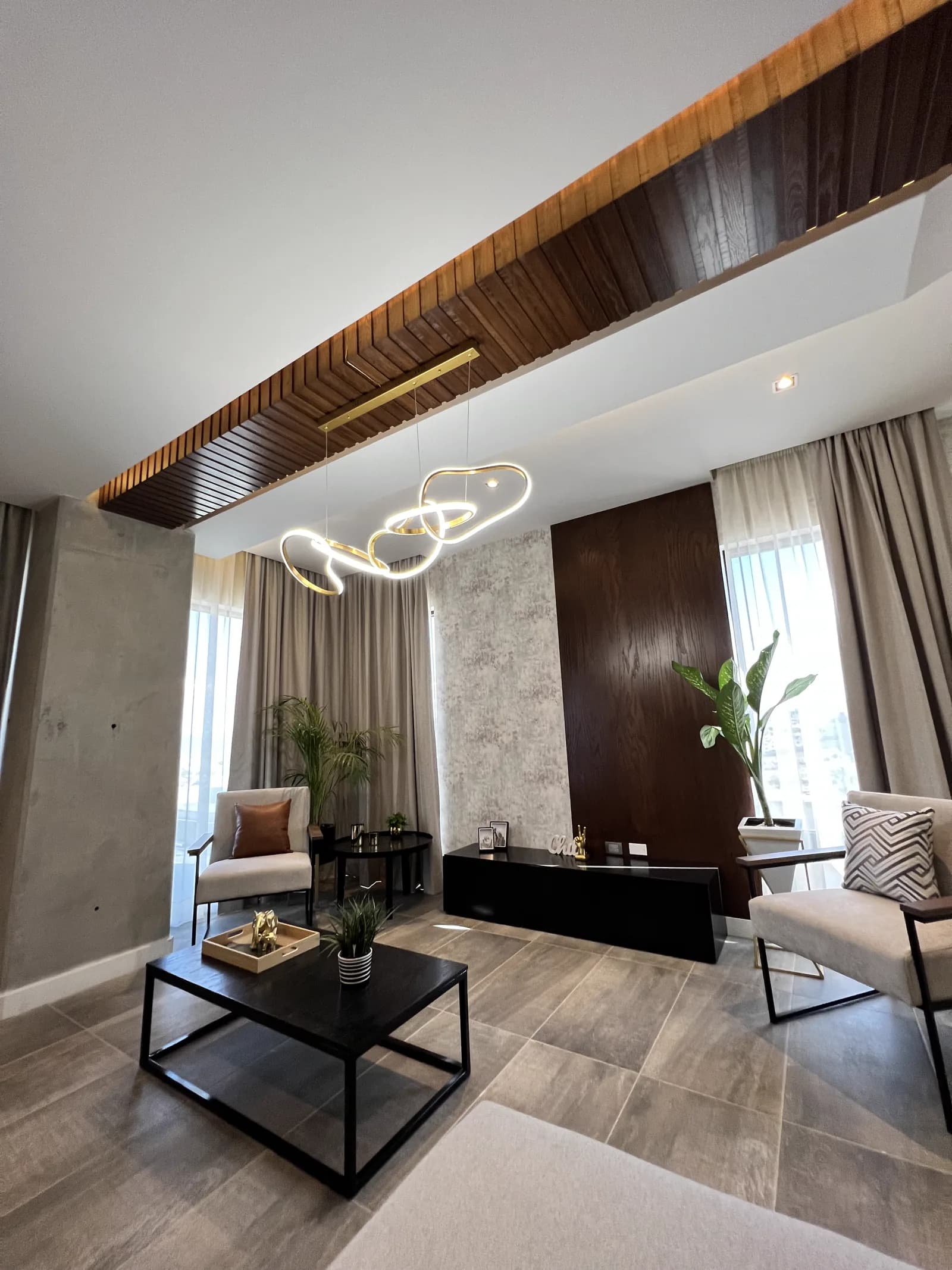 Sala con sillones individuales, el mueble negro y los paneles de madera.