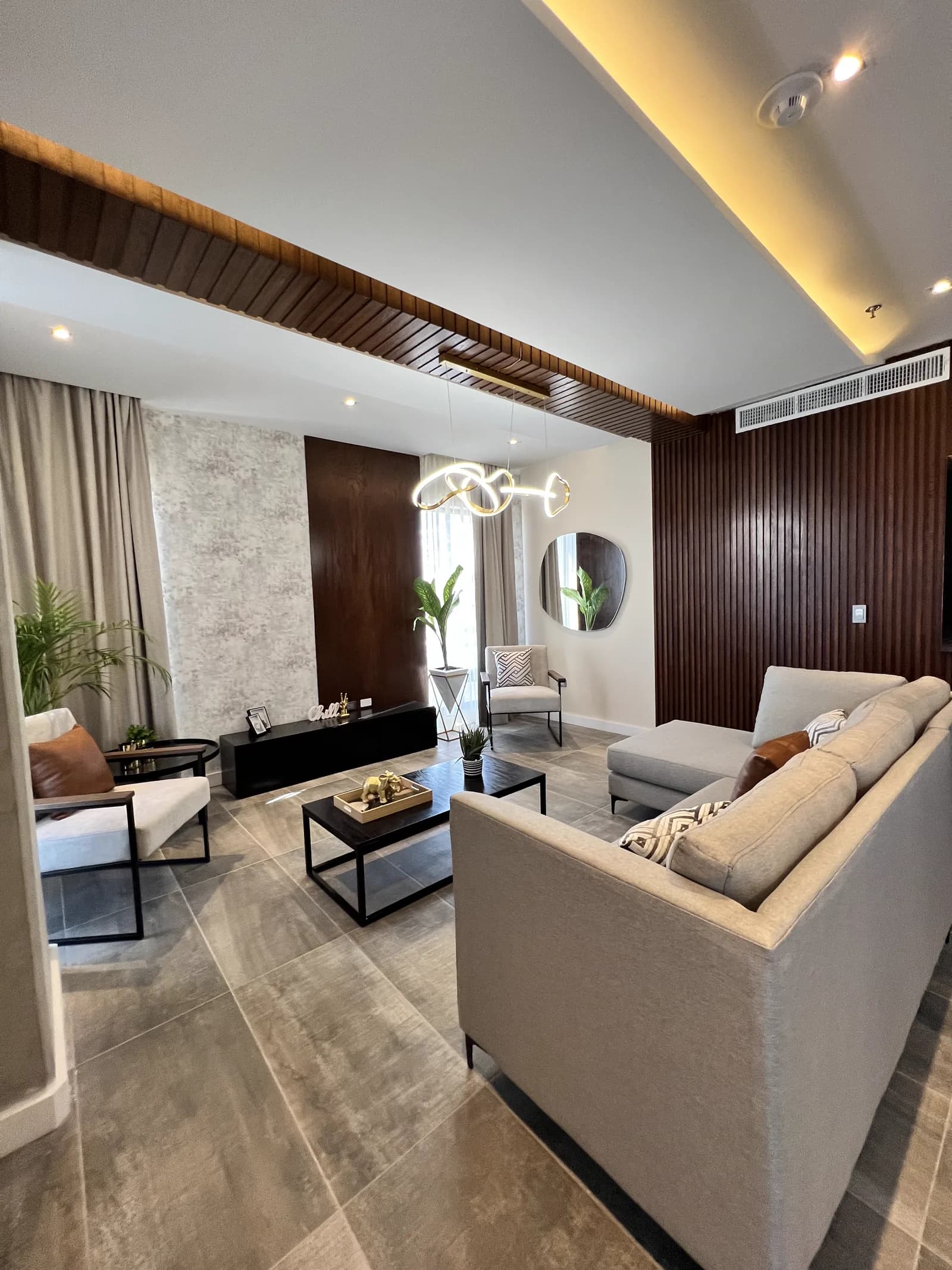 Sala con sillón gris en primer plano y el muro de madera oscura.