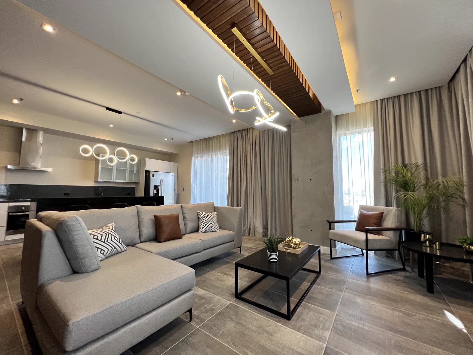 Sala y cocina integradas de Departamento All Loft 401, con la lámpara de trazo libre y el ventanal.