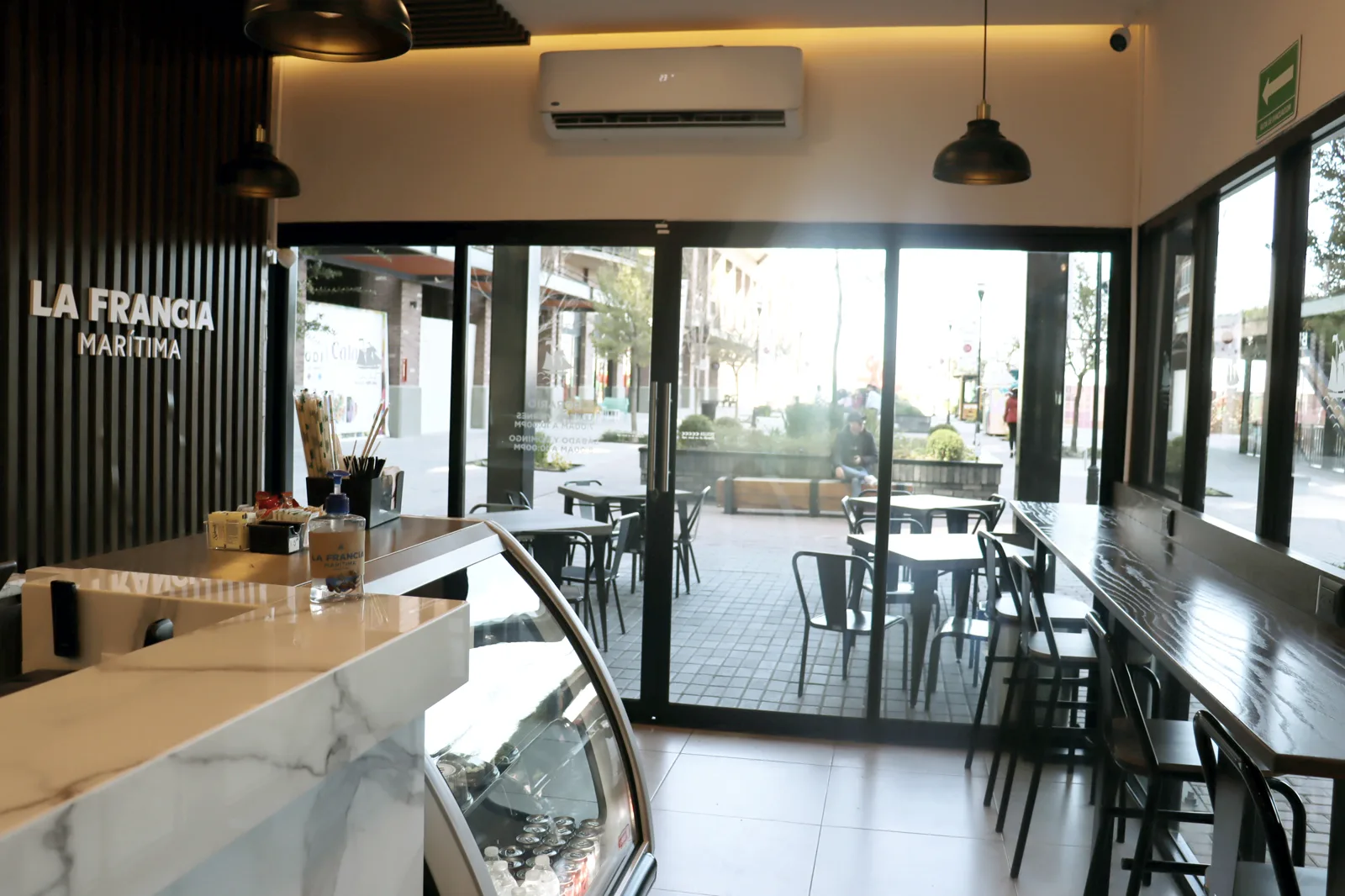 Interior de La Francia Marítima hacia la terraza, con la barra de mármol en primer plano.