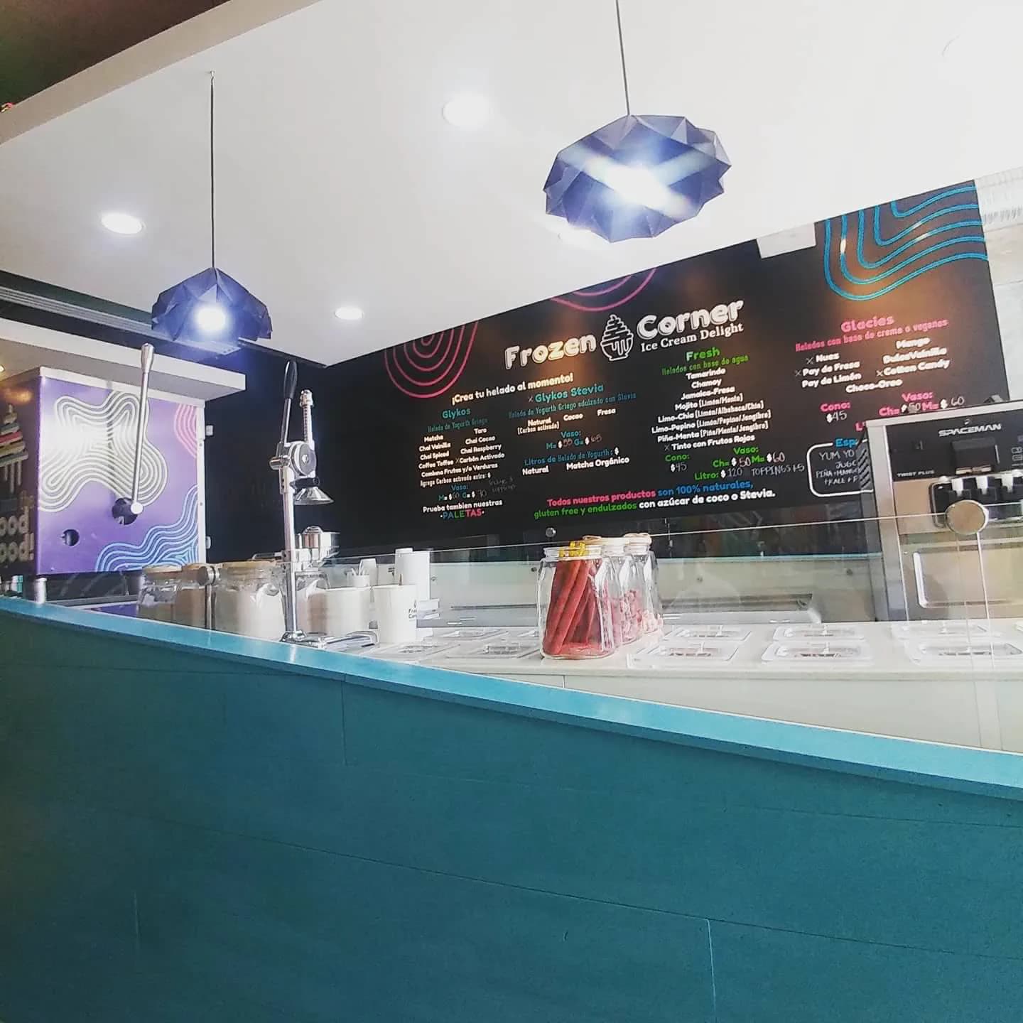 Barra con lámparas facetadas azules y el muro negro con el menú en líneas de colores.