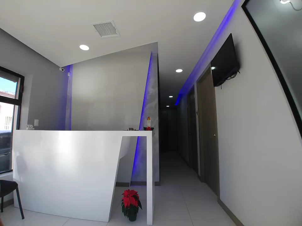 Mostrador blanco de trazo angulado y el pasillo con luz azul al fondo.