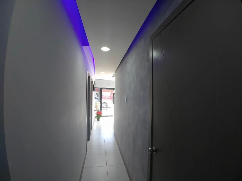 Pasillo de muros grises con la línea de luz azul en el plafón.