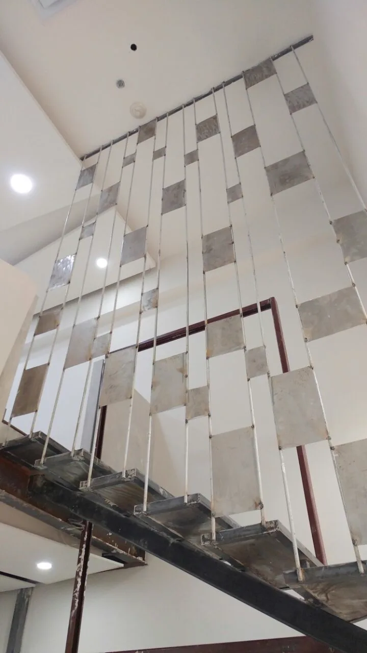 Escalera de acero junto a la cortina de placas grises y blancas.