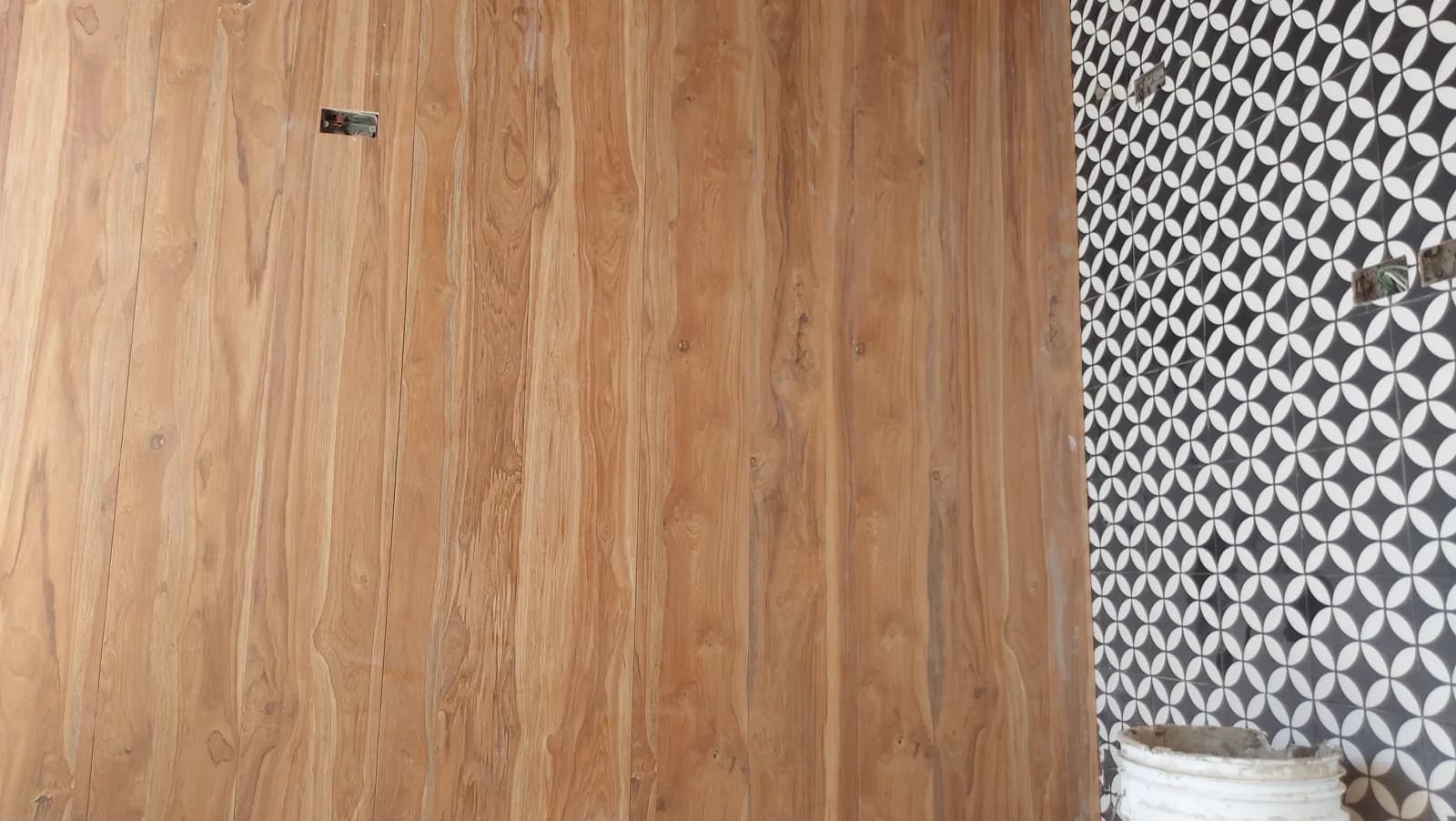 Muro de madera junto al mosaico geométrico durante la obra.