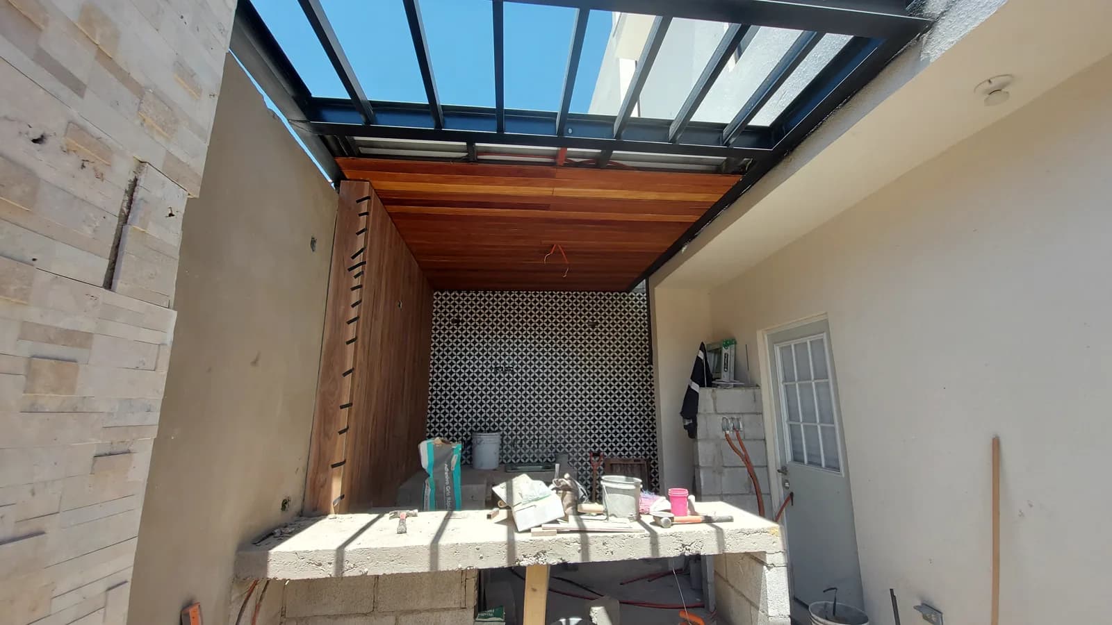 Vista del patio en obra hacia el área de asador techada.