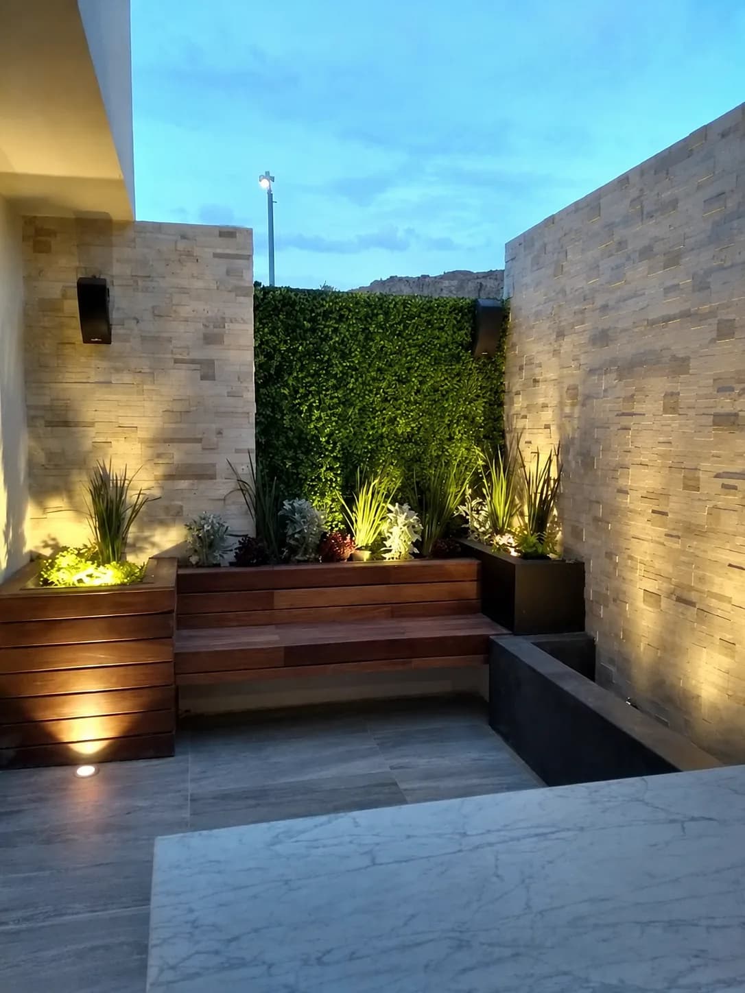 El patio terminado al atardecer, con las jardineras iluminadas.