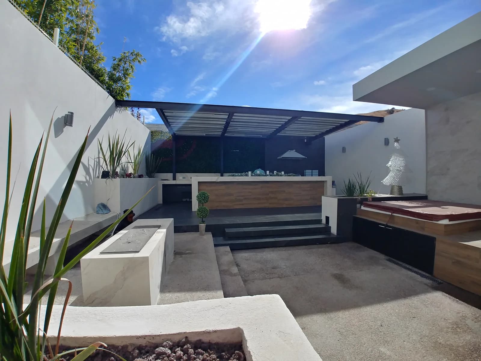 Terraza techada vista desde el jardín, con los escalones y las jardineras.