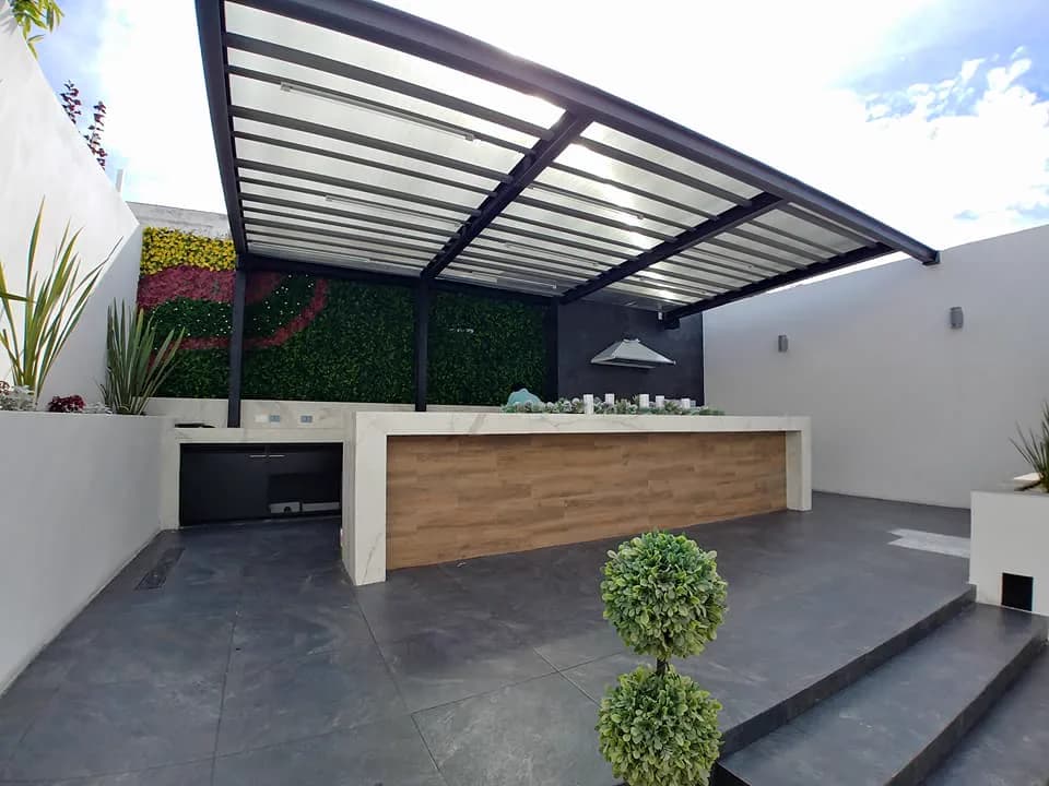 Terraza terminada con el muro verde, la barra y un arbusto recortado en primer plano.