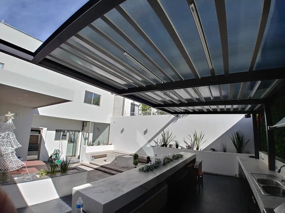 Barra de cocina bajo la pérgola, con vista hacia la casa.