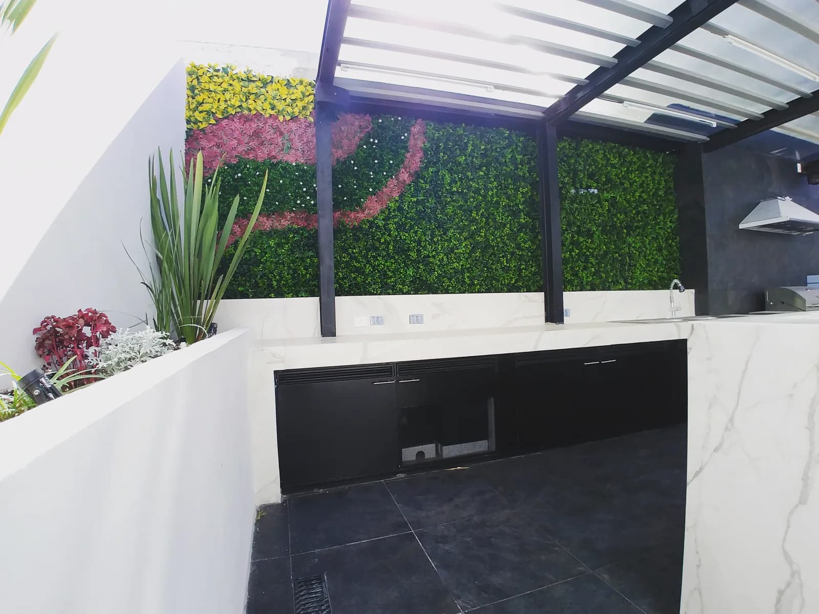 Gabinetes negros y cubierta de porcelanato tipo mármol frente al muro verde.