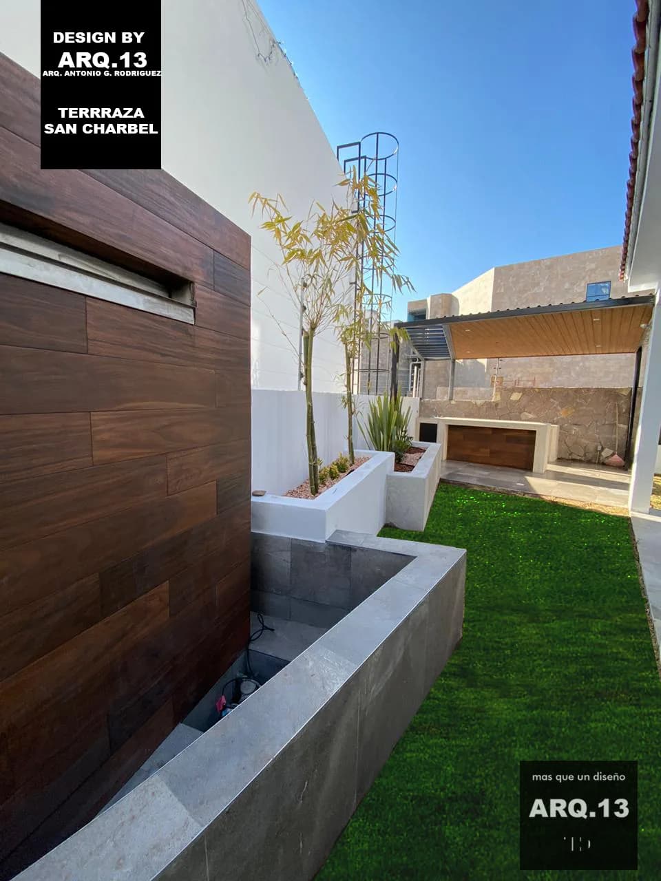 Muro de madera con caída de agua junto a la jardinera y el pasto.