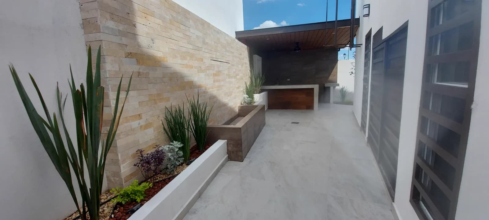 Jardineras escalonadas a lo largo del muro de piedra, con la terraza al fondo.
