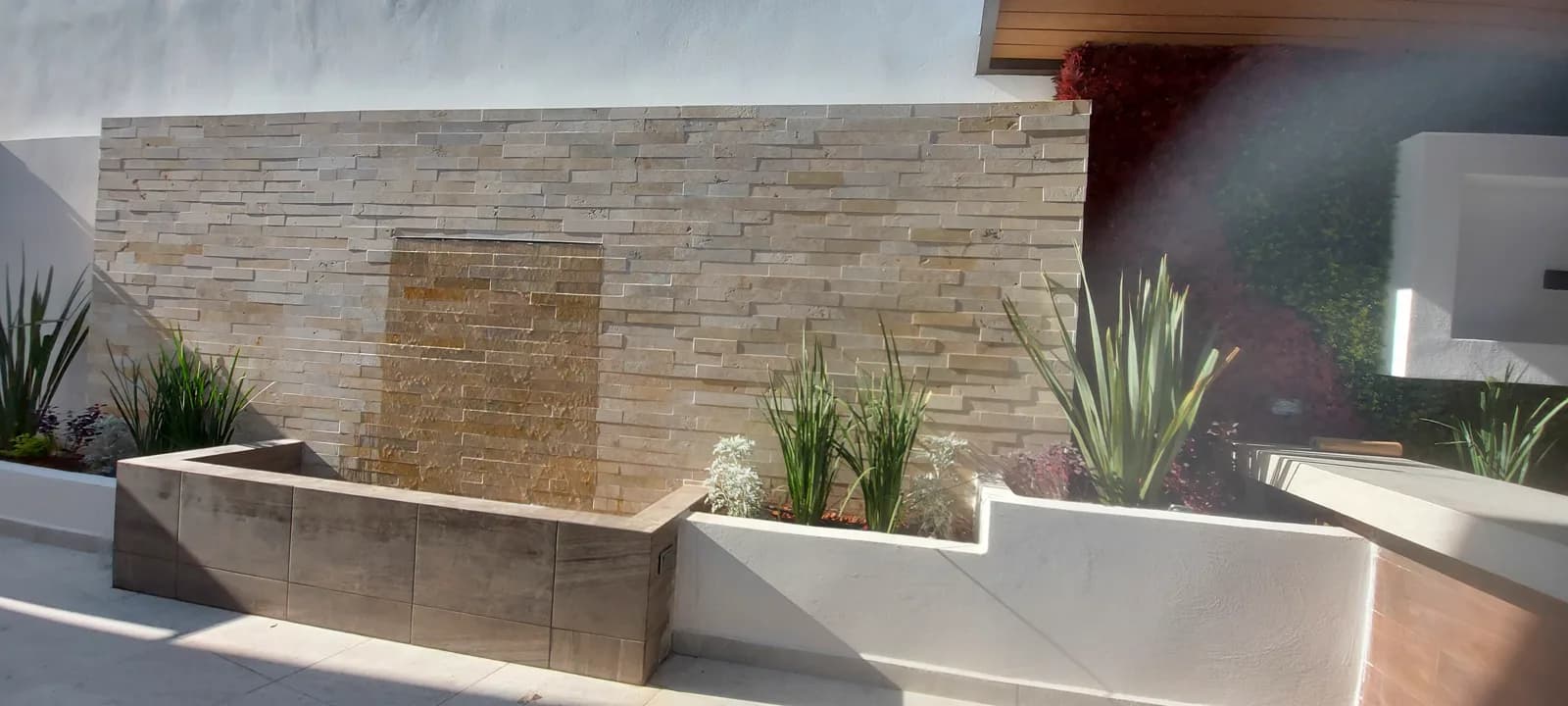 Muro de piedra laja con caída de agua y jardineras escalonadas de Patio Saratoga.