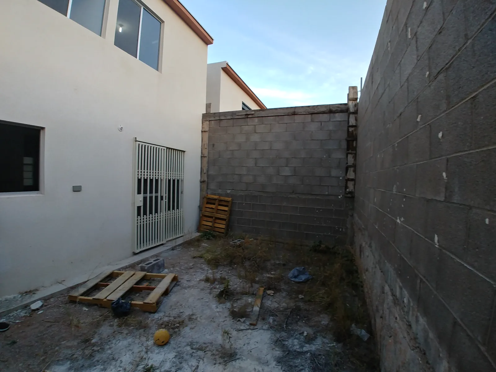 El patio antes de la obra, con muros de block y tierra.