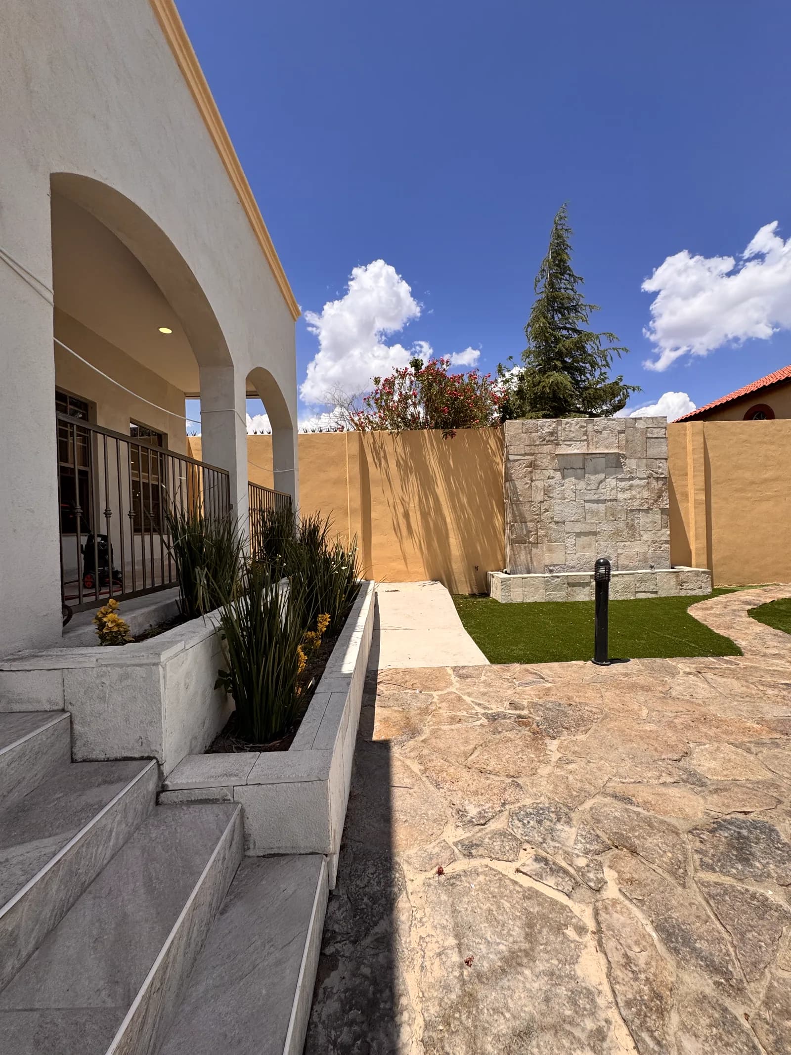 Terraza de Casas Grandes, con pórtico de arcos, jardinera corrida, fuente de piedra y piso de laja.