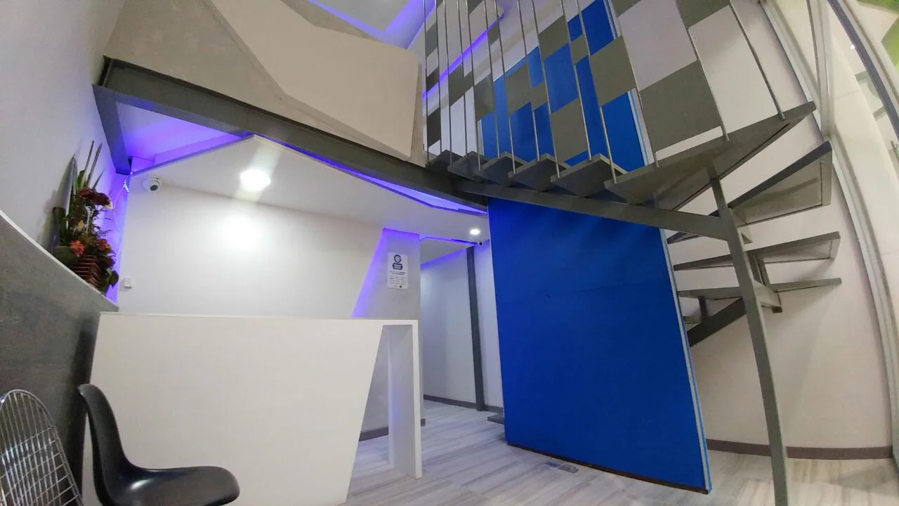 Recepción y escalera vistas desde el acceso, con la luz azul indirecta.
