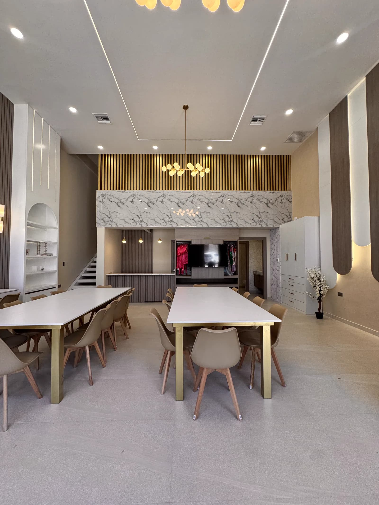 Salón Spa Infantil con mesas blancas, muro de mármol y listones de madera, y lámparas de globos.